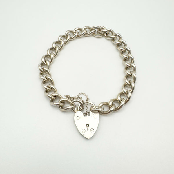 Vintage silver charm bracelet with heart padlock clasp laid flat