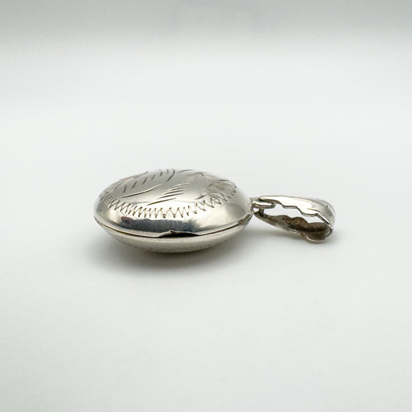 Side view of vintage puffy locket with etched design