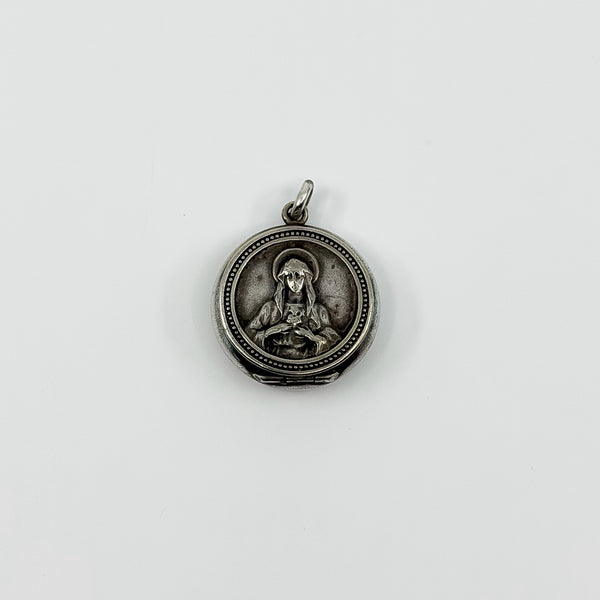 Vintage sterling silver Virgin Mary Christian photo locket pendant with jump ring on white background.