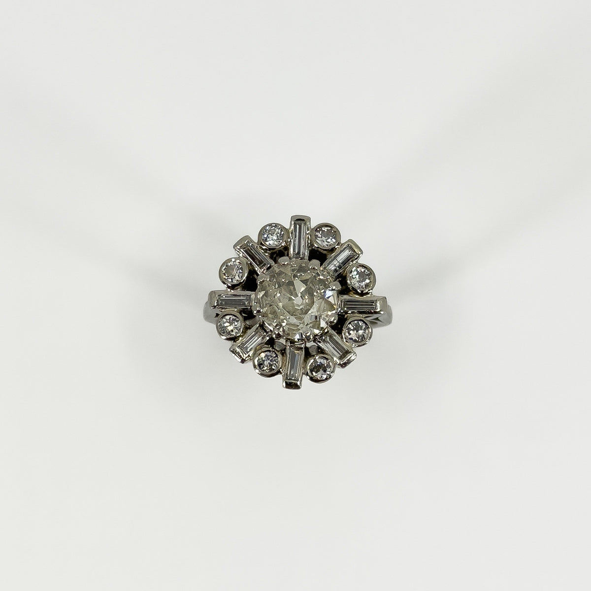 Front view of vintage platinum 2.70ct diamond cluster ring with old cut centre and alternating diamond surround.