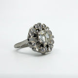 Angled close-up of vintage platinum diamond cluster ring showing the old cut centre and surrounding diamonds.