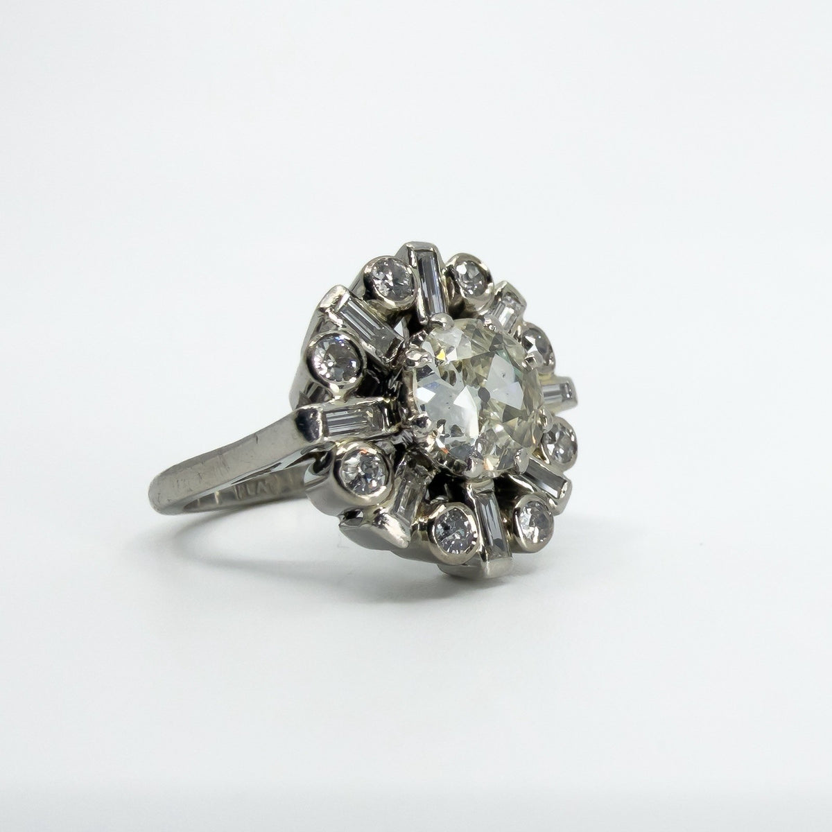 Angled close-up of vintage platinum diamond cluster ring showing the old cut centre and surrounding diamonds.