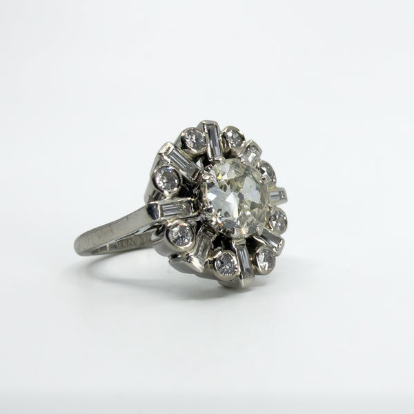 Angled close-up of vintage platinum diamond cluster ring showing the old cut centre and surrounding diamonds.