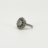 Angled view of vintage platinum diamond cluster ring showing the raised old cut centre and diamond surround.