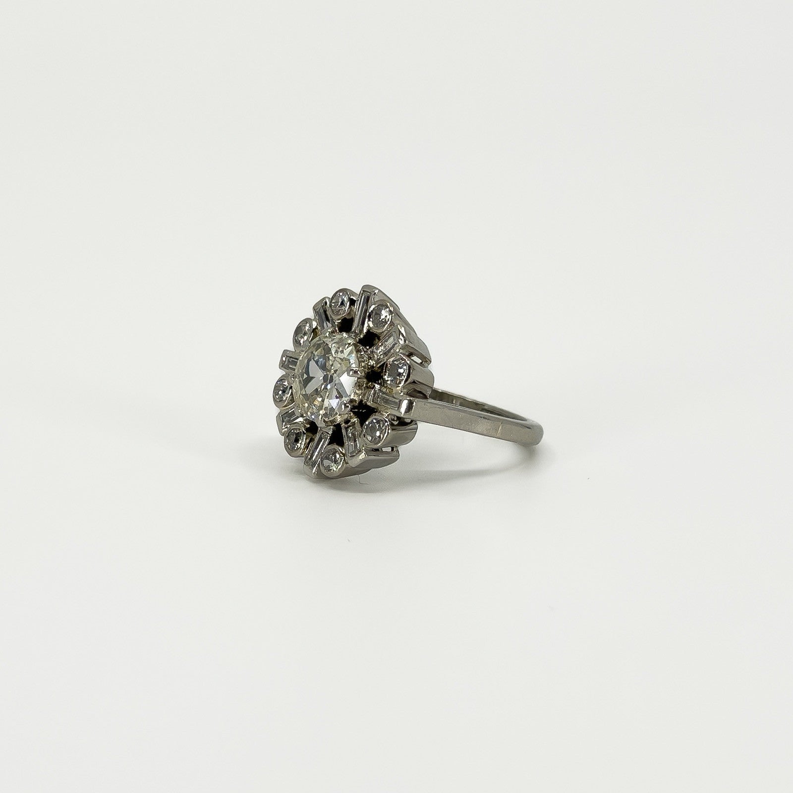 Angled view of vintage platinum diamond cluster ring showing the raised old cut centre and diamond surround.