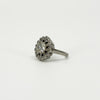 Angled view of vintage platinum diamond cluster ring showing the raised old cut centre and diamond surround.