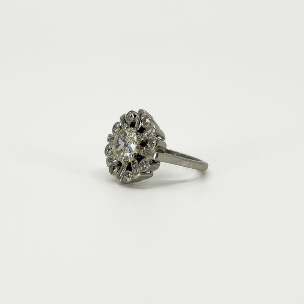 Angled view of vintage platinum diamond cluster ring showing the raised old cut centre and diamond surround.