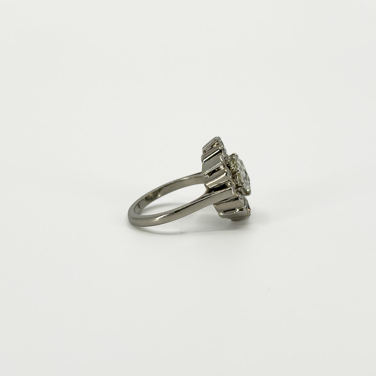 Side profile of vintage platinum diamond cluster ring showing the raised setting and tapered platinum band.
