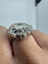 Close-up of vintage platinum diamond cluster ring worn on the hand, showing the raised old cut centre and surround.
