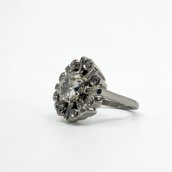 Angled front view of vintage platinum cluster ring with old cut centre and alternating round and baguette diamonds.