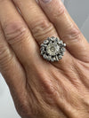 Vintage platinum old cut diamond cluster ring worn on the hand with alternating round and baguette diamonds.