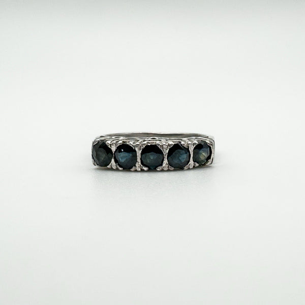 Close-up of vintage sterling silver ring with five dark blue sapphires in a claw setting