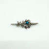 Vintage sterling silver turquoise brooch with cabochon stone and leafy design on a white background.