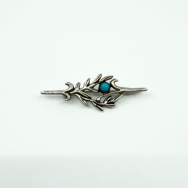 Vintage sterling silver turquoise brooch with cabochon stone and leafy design on a white background.