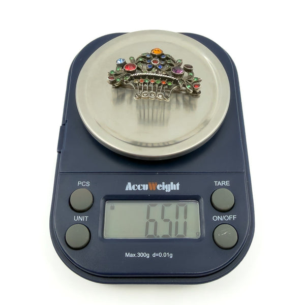 Sterling silver giardinetti brooch on digital scales showing approx. 6.50g weight with multicoloured paste stones.