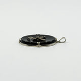 Side view of vintage black onyx bow pendant showing the white gold frame and bail.