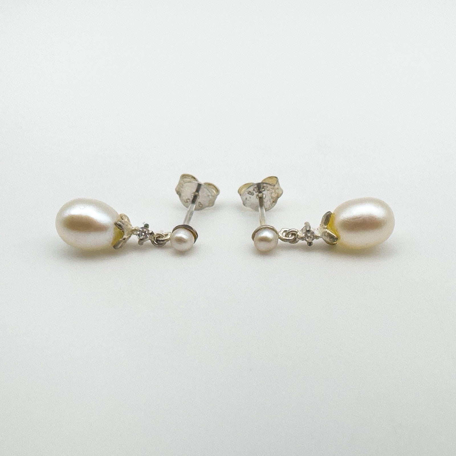 Side view of sterling silver pearl earrings with CZ lying flat