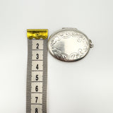 Oval sterling silver locket shown next to tape measure for width reference