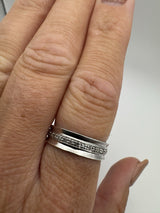 Close-up of sterling silver diamond ring worn on finger, showing flush claw setting
